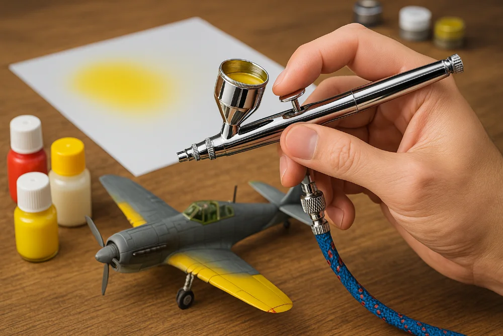 Аерограф у руці майстра під час фарбування моделі літака фарбами на водній основі, приклад використання для початківців